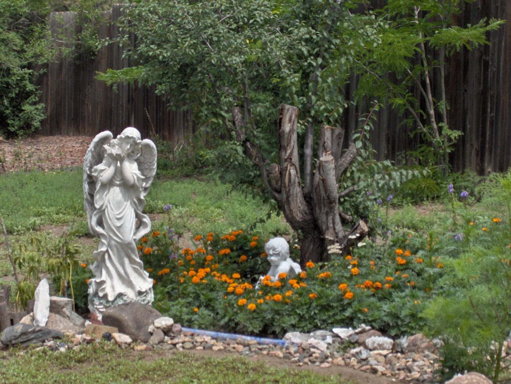 A statue of an angel in the middle of a garden.