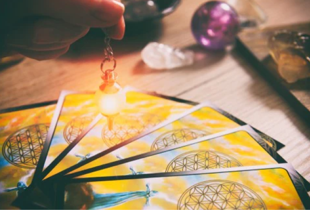 A person holding a light over four tarot cards.